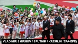 Vladimir Putin i Kim Džong Un hodaju crvenim tepihom dok ih djeca pozdravljaju mašući ruskim zastavama, Pjongjang 19. juni 2024.