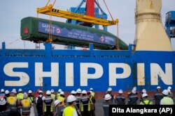 Radnici koriste dizalicu za istovar vagona kineskog brzog putničkog vlaka s teretnog broda u luci Tanjung Priok u Jakarti, Indonezija, petak, 9. februar 2022., za brzu željeznicu Jakarta-Bandung.