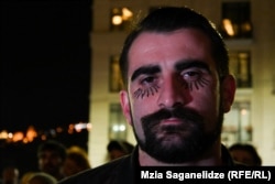 ლაზარეს სოლიდარობის ნიშნად თვალებდახატული დემონსტრანტი მის მხარდამჭერ აქციაზე საქართველოს მთავრობის ადმინისტრაციასთან