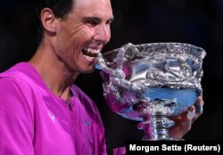 Španjolac Rafael Nadal grize trofej kako bi proslavio pobjedu u finalu muškog singla, Australian Open, Melbourne Park, Melbourne, Australija - 31. januara 2022.