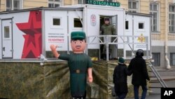 Ljudi prolaze pored mobilnog regrutnog centra postavljenog u blizini vojno-istorijske izložbe na Trgu Dvorcovaja (palata) u Sankt Peterburgu, Rusija, januar 2024.