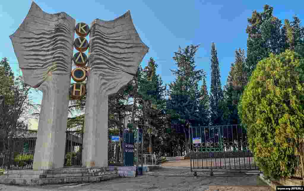 У ворот базы отдыха «Кулон», собственник которой – российское АО «Компания «Сухой». Как общеизвестно, компания занимается разработкой, производством, маркетингом, обучением летного персонала, послепродажным обслуживанием боевых и гражданских самолетов марки «Су» и «Бе». После 2022 года она была объединена с корпорацией «МиГ», став частью «Оъедиенной авиастроительной корпорации», входящей в состав «Ростеха».Из-за вторжения России в Украину компания находится под международными санкциями Евросоюза, США и ряда других стран