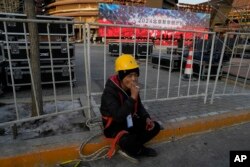 Radnik na pauzi tokom probe za program novogodišnje noći u Pekingu, 27. decembra 2023.