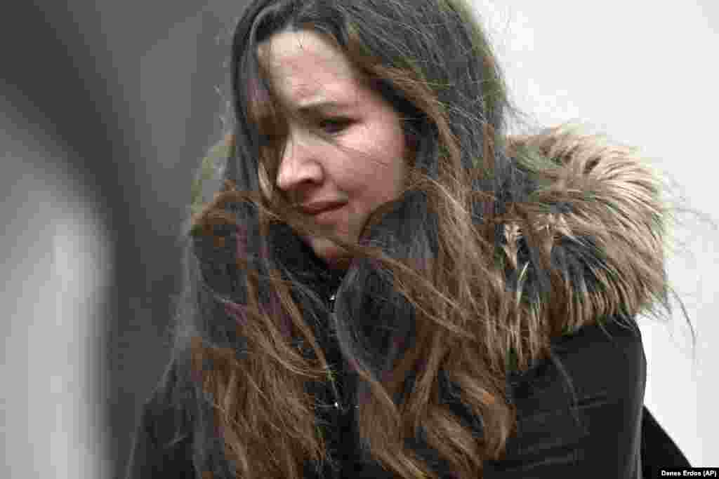 Жінка плаче перед місцем біля університету, куди люди приносять свічки та квіти 