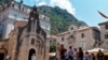 Kotor - Tourists stand in front of a church as they visit the medieval city of Kotor on August 21, 2018. 