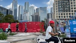 Radnici prolaze pored gradilišta u Šenženu, provincija Guangdong, Kina, 25. avgusta 2023.