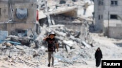 Palestinci prolaze pored kuća koje su uništene u izraelskom napadu, Kan Junis, jug Pojasa Gaze, 22. maja 2024.