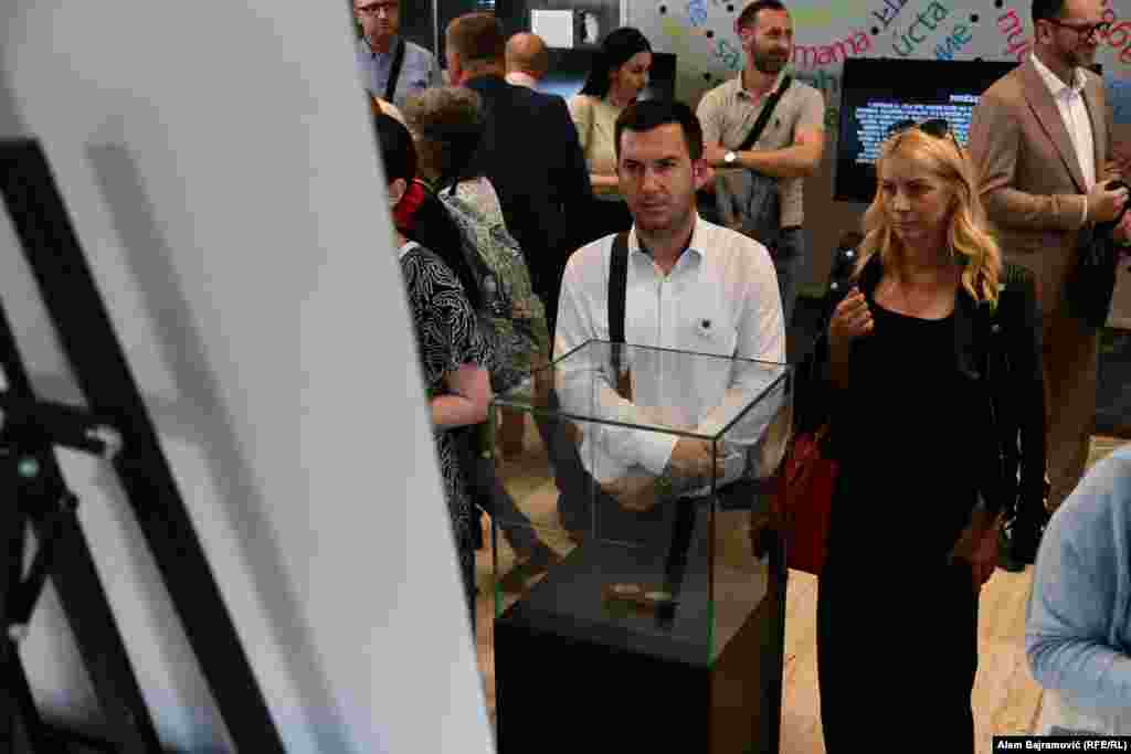 Posjetitelji stoje kod naočala Hasana Handžića i čitaju priču o njegovom životu. Njegovi posmrtni ostaci pronađeni su u masovnoj grobnici Kamenica kod Zvornika, zajedno sa naočalama koje su predstavljene na izložbi, a koje je sačuvao Hasanov unuk i donirao MCS.  