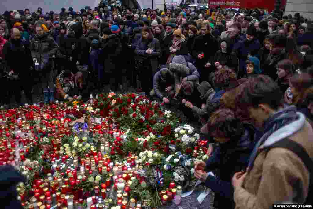 Люди віддають шану загиблим перед головним корпусом Карлового університету в Празі 22 грудня 2023 року. Чехія оголосила 23 грудня національним днем жалоби за 14 людьми, які загинули в результаті стрілянини в центрі Праги 21 грудня, яка шокувала чехів та викликала численні повідомлення про солідарність 