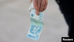 Muškarac drži novčanicu od sto dinara u kafiću u Severnoj Mitrovici, Kosovo, 1. februar 2024.