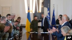 Zvaničnici aplaudiraju ukrajinskom predsjedniku Volodimiru Zelenskom (lijevo) i grčkom premijeru Kyriakosu Micotakisu nakon potpisivanja sporazuma u Atini, 21. avgusta 2023. Zelenski je bio u Grčkoj na razgovorima s rukovodstvom zemlje i prisustvovao neformalnom sastanku balkanskih lidera sa najvišim zvaničnicima EU.