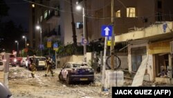 Pripadnici izraelskih snaga sigurnosti hodaju ulicom prepunom krhotina u Tel Avivu, nakon što je pogođena raketom koju su ispalili palestinski militanti iz Pojasa Gaze 7. oktobra 2023.