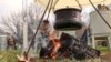 Zenica, Bosnia -- A pot brewing on a field during a traditional festival with an old man sitting in the background