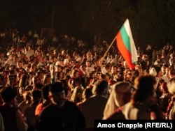 Muškarac drži bugarsku zastavu na festivalu, pred paljenje velikog ognja.