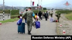 Na ovoj fotografiji preuzetoj sa video snimka koji je objavila pres-služba Ministarstva odbrane Rusije 21. septembra, ruski mirovnjaci pomažu etničkim Jermenima da dođu do kampa u blizini Stepanakerta u Nagorno-Karabahu.