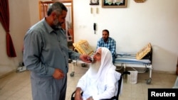 პალესტინელი ჰამასის ოფიციალური პირი ისმაილ ჰანიე ეხმარება ჰამასის თანადამფუძნებელს აჰმედ იასინს სატელეფონო ზარის განხორციელებაში ღაზაში, 2003 წლის 13 ივნისი.