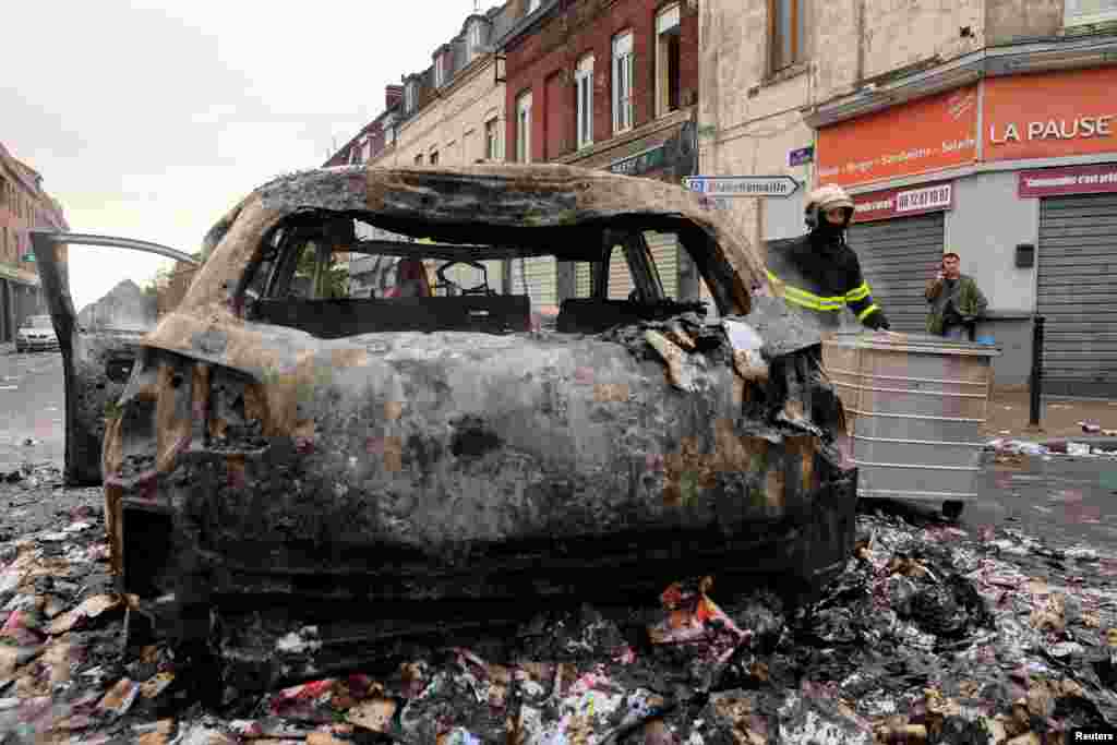 Vatrogasac prolazi pokraj automobila, spaljenog tokom noćnih sukoba između demonstranata i policije, u četvrti Alma u Roubaixu, na sjeveru Francuska, 30. juna 2023. 