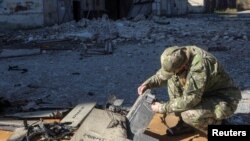 یک مأمور پلیس در حال بررسی بقایای پهپاد شاهد ۱۳۶ ساخت ایران است، خارکیف، اکتبر ۲۰۲۲