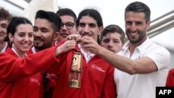 Francuski predsjednik Organizacionog odbora Olimpijskih i Paraolimpijskih igara u Parizu 2024. Tony Estanguet (desno) nosi olimpijski plamen dok pozira s mladim jedriličarima na francuskom trojarbolnom brodu Belem iz 19. veka, 27. april 2024.