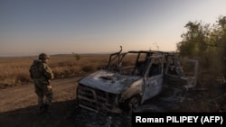 Український військовослужбовець проходить повз знищену машину біля окопів, побудованих російськими військами біля прифронтового села Роботине, Запорізька область, 1 жовтня 2023 року