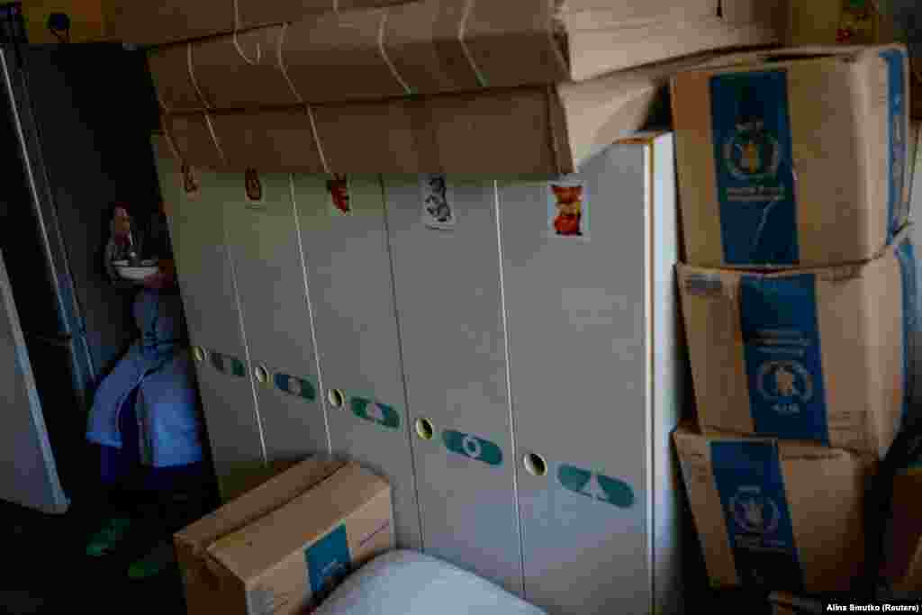 Жінка їсть їжу в закутку в притулку, в якому вона живе. Масштабна війна Росії проти України триває вже майже 2 роки. Людей, які проживають у місцях, вразливих від снайперського та артилерійського вогню, закликають евакуюватися  