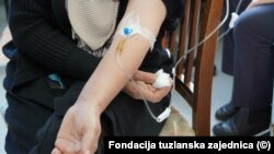 Pacijent u Tuzli prima terapiju sjedeći na drvenoj stolici.