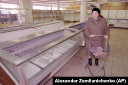 Женщина у пустых прилавков в продуктовом магазине. Октябрь 1990 года