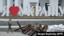 Ukrajinski vojnik prolazi pored natpisa "Volim Ukrajinu" i protutenkovske barikade u centru Kijeva, 7. mart 2022.