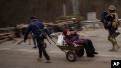 Un militar ucrainean și un civil înarmat ajută o familie să părăsească Irpin sâmbătă, în 5 martie.