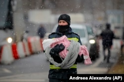 Un pompier duce un copil refugiat din Ucraina, la punctul de frontieră Siret, în 7 martie 2022.