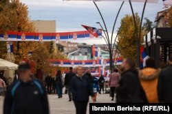 Prolaznici ispod zastava Srbije na glavnom trgu u Severnoj Mitrovici.