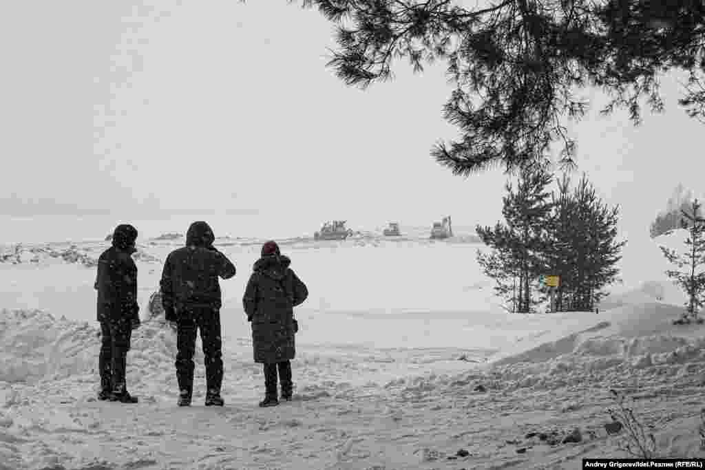 Местные жители наблюдают за работой строительной техники в уничтоженной акватории Волги у казанского посёлка Куземетьево. Реку засыпали грунтом, чтобы сформировать здесь искусственный участок суши. Работы велись с нарушением закона. Коммерческие структуры, приближенные к руководству Татарстана, захватали берег и участок в глубине суши, чтобы построить гольф-клуб.