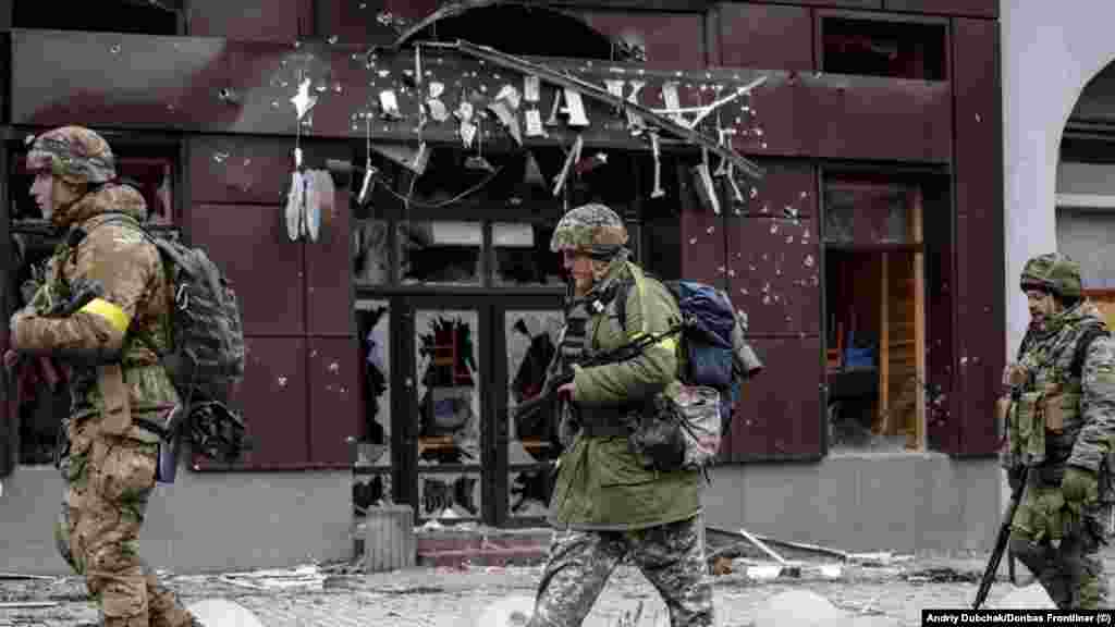 Vojnici prolaze pored srušenog kafića u Bahmutu. Neprekidno nadolazeće granatiranje, kaže Dubčak, "stvarno je ludo, stvarno zastrašujuće" u centru Bahmuta jer "Rusija granatira bez ikakve logike".