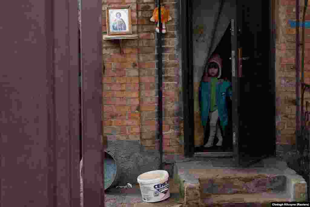 3-річна Олександра чекає біля дверей свого дому на прибуття фургона з подарунками напередодні Різдва  за старим стилем у Бахмуті, Донецька область, фото від 4 січня 2022 року. Бахмут вважається однією з найгарячіших точок на лінії фронту російсько-української війни. Очільник Донецької ОВА Павло Кириленко повідомляв, що понад 60% міста знищено
