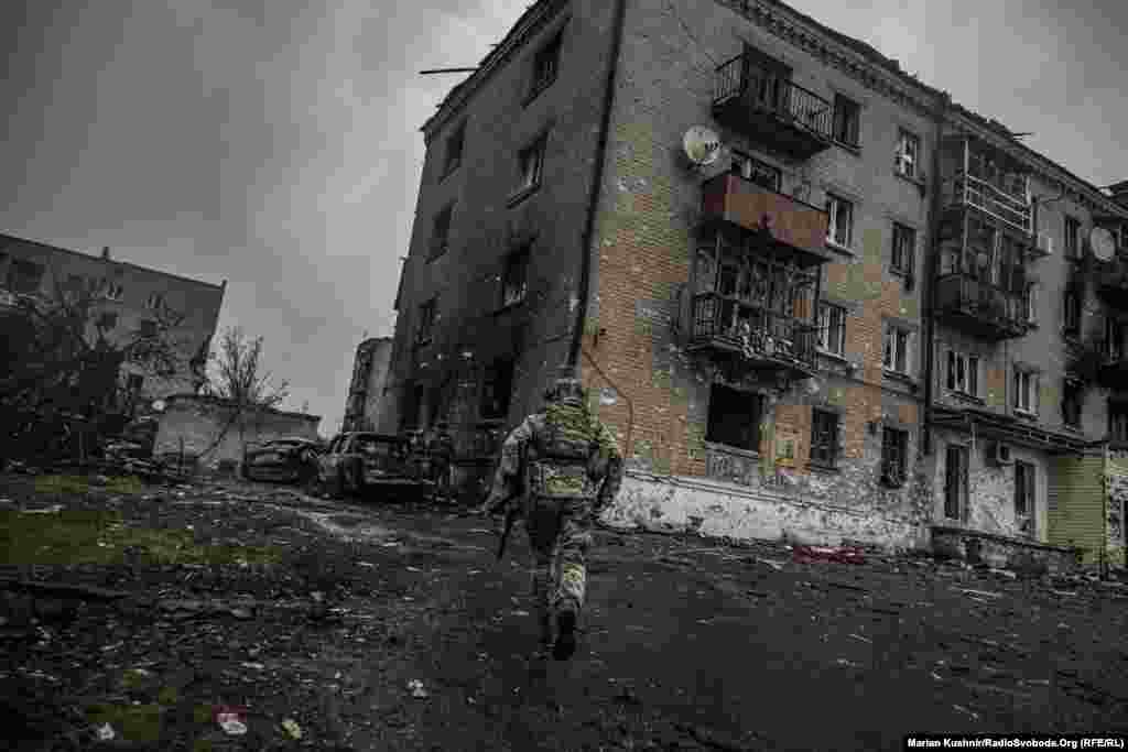 Військовий із позивним “13” біжить по розбитій вулиці у Соледарі.