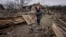 Женщина собирает доски на улице, разрушенной в результате обстрела в Чернигове, 13 апреля 2022 года