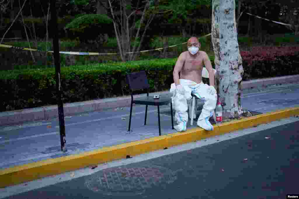 Radnik u zaštitnom odjelu se odmara izvan kvarta koji je u totalnom zatvaranju kako bi se spriječilo širenje korona virusa u Šangaju, 11. april 2022.
