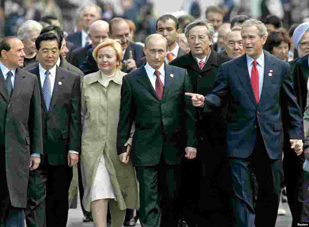 Italijanski premijer Silvio Berlusconi; kineski predsjednik Hu Jintao; predsjednik Putin i njegova supruga Ljudmila; predsjednik Evropske unije Jean Claude Juncker i američki predsjednik George W. Bush šetaju zajedno Kremljem u Moskvi nakon što su prisustvovali komemoraciji u Drugom svjetskom ratu na Crvenom trgu 9. maja 2005. godine.