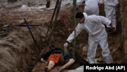 მესაფლავეს ამოჰყავს მოქალაქის ცხედარი ჯგუფური სამარხიდან. ბუჩა, 2022 წლის 10 აპრილი