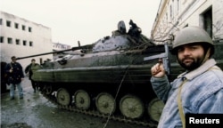 Chechen militants surround Russian armored personnel carriers destroyed in the battle for Grozny in January 1995.