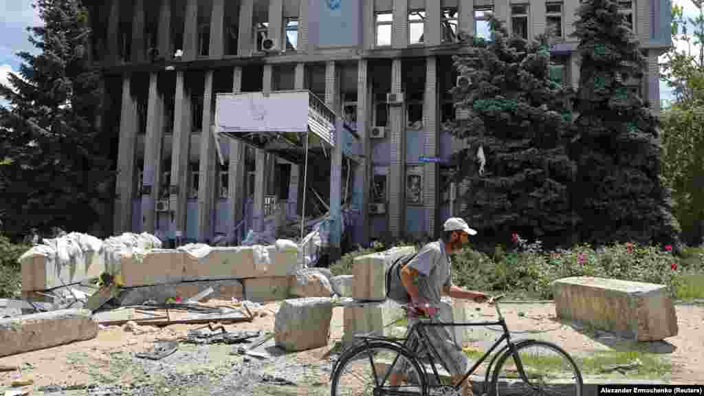 Lokalni stanovnik prolazi biciklom pored porušene zgrade policije.