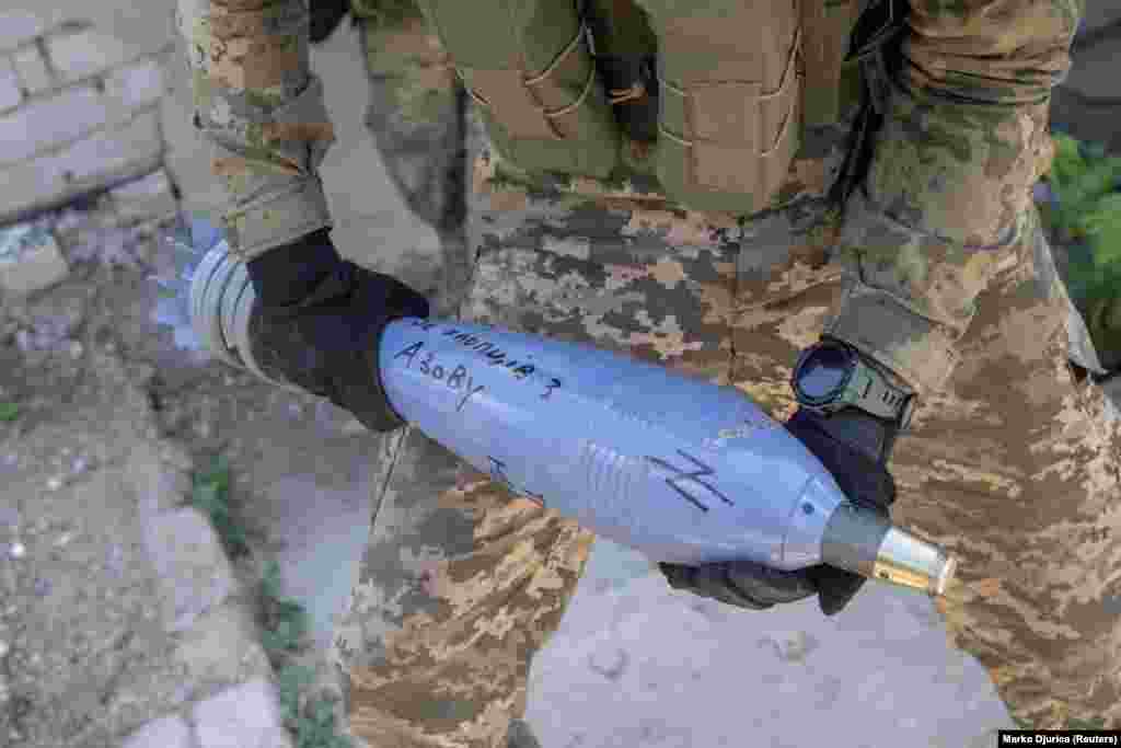 Logo Azovskog puka na minobacačkoj granati koju drži pripadnik Karpatskog bataljona Sič, uz natpis "Za momke iz Azova." Ukrajinski puk Azov nastao je iz bataljona Azov, desničarske milicije koja je postala istaknuta u prvim danima rata. Njegovi logotipi bili su slični onima koje su koristile nacističke jedinice tokom Drugog svjetskog rata. Puk Azov je kasnije uključen u Nacionalnu gardu Ukrajine. Jedan broj njenih pripadnika bio je prisiljen da se preda nakon što su izdržali rusko bombardovanje čeličane Azovstal u Mariupolju.