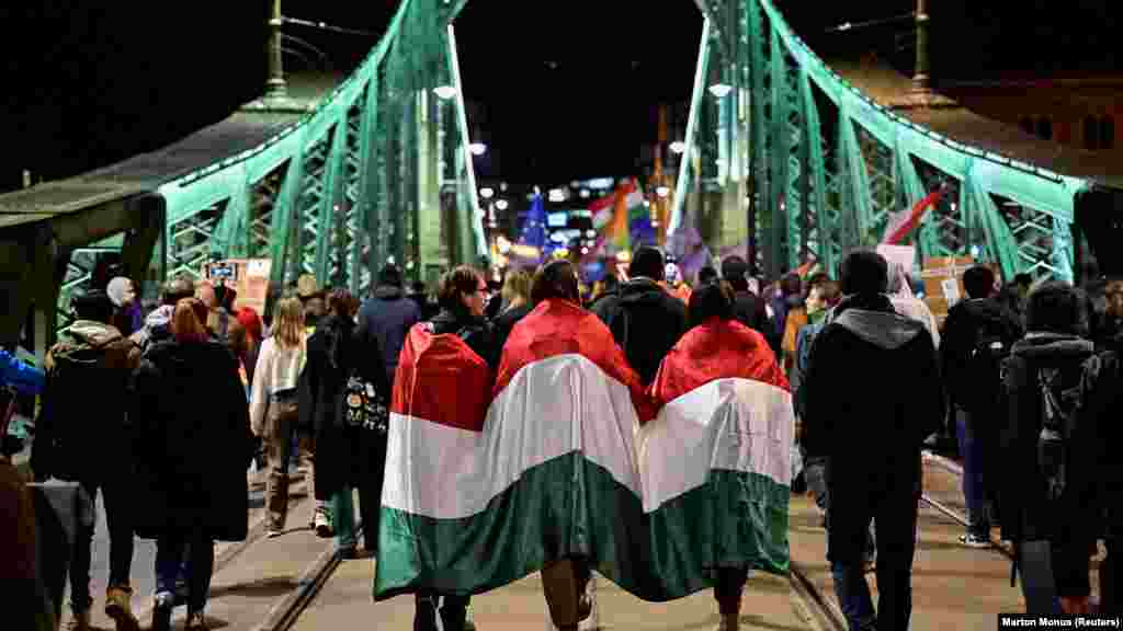 Ljudi umotani u mađarsku zastavu učestvuju u demonstracijama u Budimpešti protiv novog zakona koji zabranjuje Pride marševe i postavlja šira ograničenja na slobodu okupljanja u zemlji.