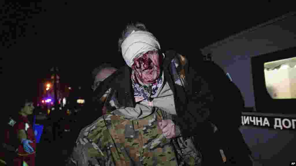 Украинский военный выносит пострадавшую женщину из ее дома, который попал под российский удар, Киев