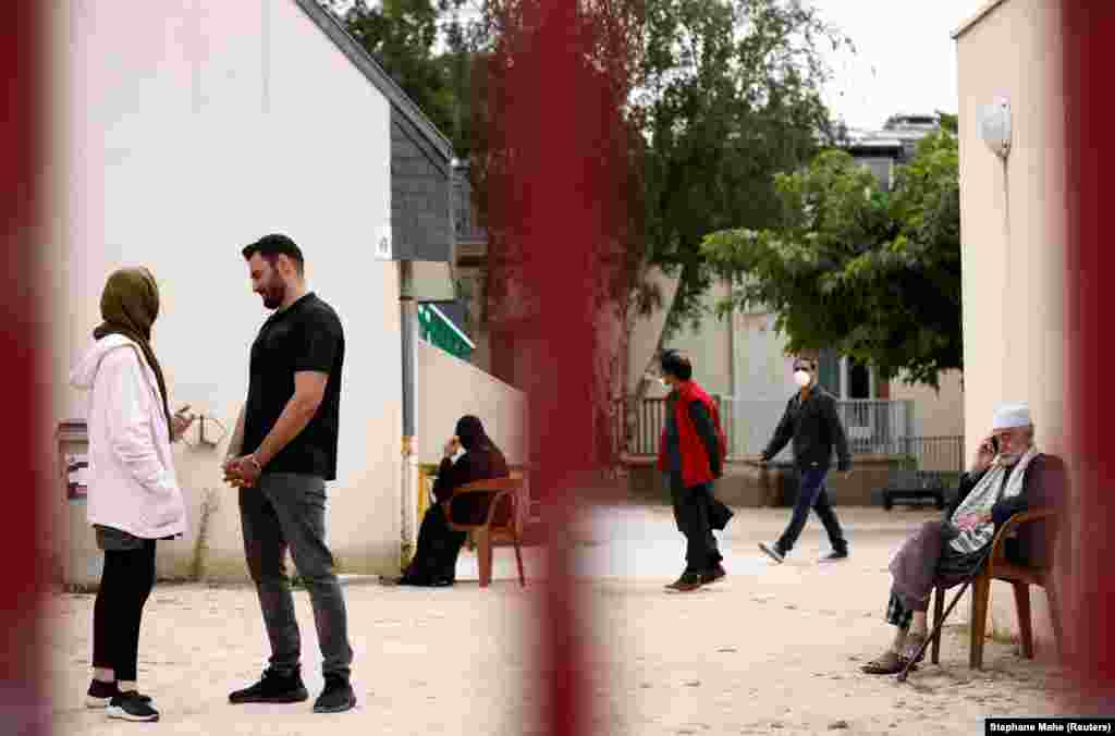 Asma Halimi (25) i Mohammad Omer Aiubi (29), izbegli iz Avganistana, razgovaraju u dvorištu prihvatnog centra Razai 30. avgusta u Piriac-sur-Meru u Francuskoj, nakon što su prethodne nedelje evakuisani.