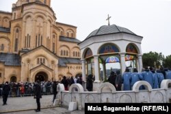 სანამ პატრიარქი და სასულიერო პირები წყლის კურთხევისთვის ლოცვებს კითხულობენ მრევლი ჯებირს მიღმა იცდის.
