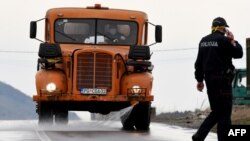 Policajac razgovara na mobitel, ulaz u Opštinu Tuzi, 25. mart 2020. godine.