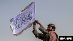Talibanski borac podiže zastavu u Kandaharu, 17. avgusta 2021. 
