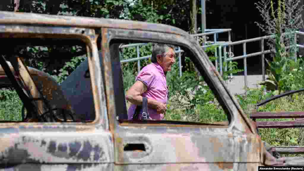 Lokalna stanovnica prolazi pored uništenih automobila