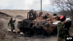 Вооруженные сепаратисты на фоне уничтоженного украинского бронетранспортера